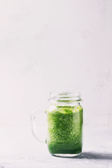 Green spinach kale apple yogurt smoothie in mason jar over white background. Healthy vegan detox eating. Toned image