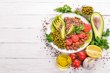 Healthy food. Buckwheat, cherry tomatoes, avocados, almonds and green peas. On a wooden background. Top view. Free space for your text.