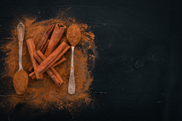 Cinnamon on a black wooden background. Free space for text. Top view.