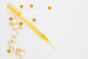 Natural cosmetics concept, vitamin oil capsules and a dropper, white background, close up
