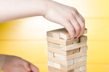 The child plays in board game falling tower of wooden blocks