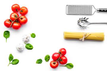 Naklejka na ściany i meble Preparing to cook pasta. Spaghetti, tomatoes, garlic, cheese grater, spoon for spaghetti on white background top view copy space