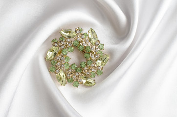 round brooch with gems isolated on a white silk