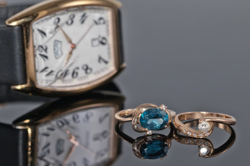 Pair of women's gold rings with diamonds on a background of elegant watches