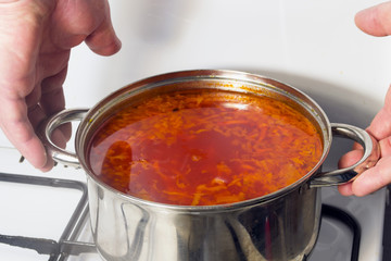 Casserole with red soup on a gas stove