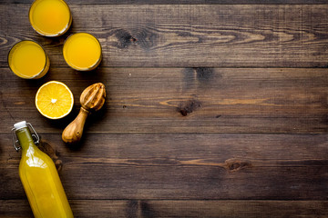 Squeeze juice from oranges. Juicer and slices of oranges on dark wooden background top view copy space