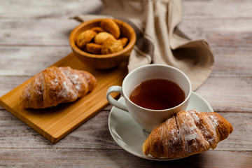 breakfast with tea and croissant on a white wooden background