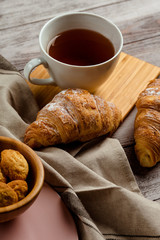 breakfast with tea and croissant on a white wooden background