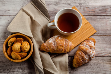 breakfast with tea and croissant on a white wooden background