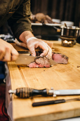Chef cutting filet on a wooden board