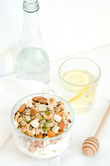 Top view healthy breakfast of homemade granola cereal with milk, strawberry, nuts and fruit, honey with drizzlier on white background. Morning food, Diet, Detox, Clean Eating, Vegetarian concept.