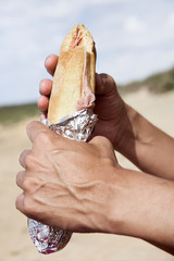 young man eating a sandwich outdoors © nito