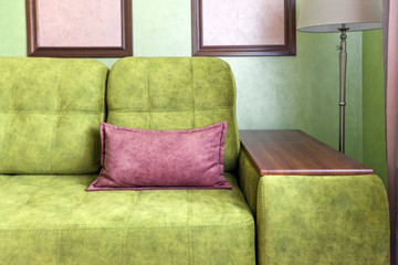 Фрагмент интерьера в розовых и зеленых цветах с зеленым диваном