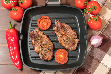 Grilled steak on grill pan with tomatoes on dark background