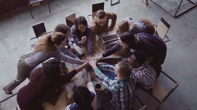 Top view of business team working at office. Young mixed race group of people puts palm together on centre. Slow mo