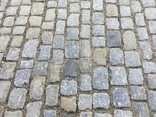 Black cobbled stone road background with reflection of light seen on the road. Black or dark grey stone pavement texture. Ancient paving stone background