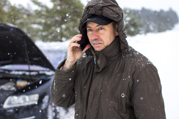 driver in the winter on the road calls for help by phone