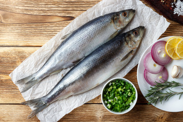 Salted herring with red onion, lemon and spices on the old wooden table.