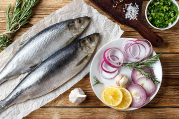 Salted herring with red onion, lemon and spices on the old wooden table.