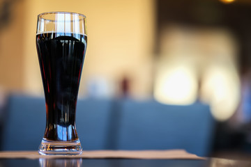 Glass of dark beer in bar or in pub close up. Real scene. Concept of beer culture, Craft brewery, uniqueness of beer grades, meeting of low alcohol beverage lovers