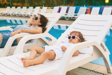 Endless summer. Cute baby and mother relaxing at sunbed