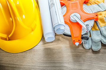 Rolled blueprints safety gloves tape measure building helmet on 