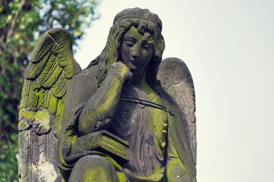 Thinking broody angel statue on Malostransky cemetery, Prague, Czech Republic