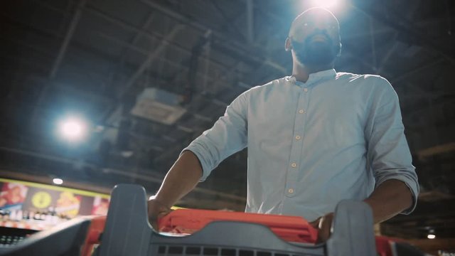 Attractive serious African american young man chooses beer in supermarket attractive ethnic food shopping black grocery market close up portrait produce store supermarket healthy slow motion