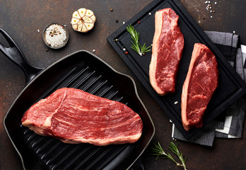 Raw fresh meat Picanha steak, traditional Brazilian cut with thyme, garlic, and black pepper on wooden board. Sliced meat Black Angus steak on grill iron pan. Top view.