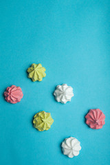 Multicolored sweet meringue on a blue background. Vertical blank for greeting card.