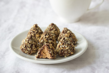 Homemade sweets with peanut butter, chocolate glaze and waffle crumbs on a table with a cup of tea, selective focus