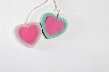 Two wooden hearts hang on a white wooden wall