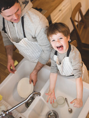 Dad and son doing the washing up in kitchen