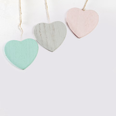 Obraz premium Three wooden hearts hang on a white wooden wall