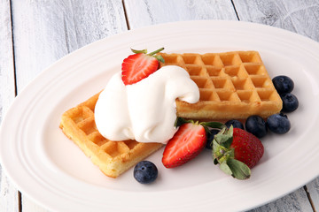 Plate of belgian waffles with whipped cream and fresh berries