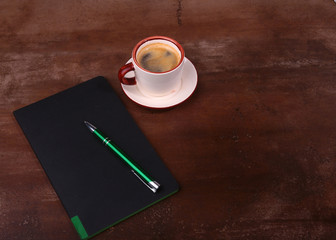 Notebook with pen and coffee cup on wooden background, business concept