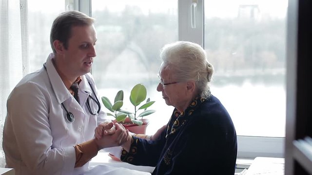 The doctor comforts and supports the old sick woman