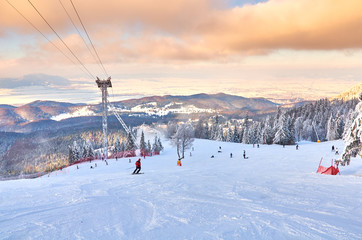 Skiers and snowboarders enjoy the ski slopes in Poiana Brasov winter resort on a sunny winter