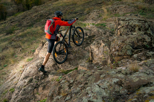 Cyclist in Red Picking the Bike up on Autumn Rocky Trail. Extreme Sport and Enduro Biking Concept.