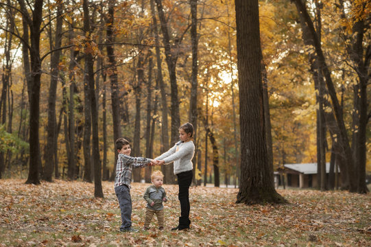 Siblings Playing On Field At Park During Autumn