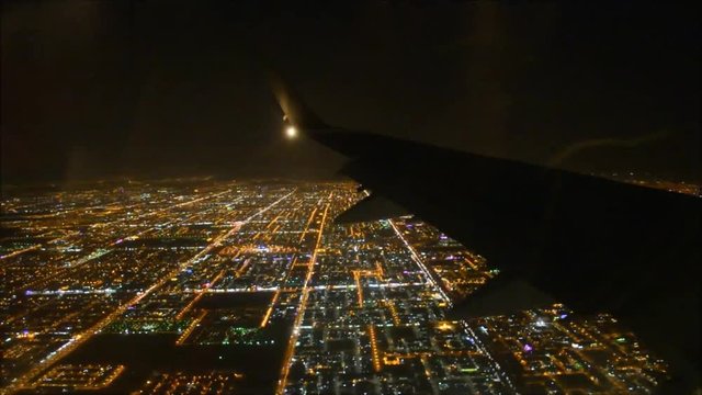 Impressive aerial flight view from passenger air plane wing on brigh night big city light illumination in dark black sky