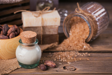 Natural cosmetic oil, sea salt and natural handmade soap with cocoa beans on rustic wooden background