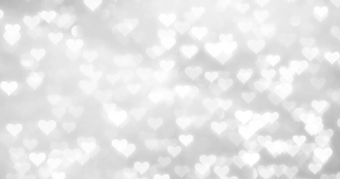 Shiny white hearts movement on blurry silver bokeh reflection background. 
