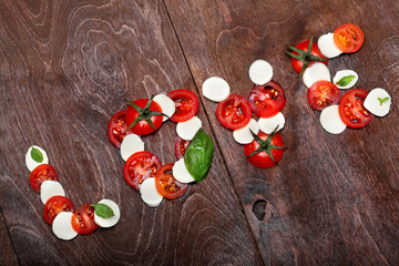 Inscription love of freshness mozzarella, raw tomatoes and basil.Ingredinet s of pizza.Against a dark wooden brown background. Creative valentine day background.Love.Spirit of Italy cuisine