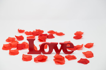 A Red Love sign and Rose petals on the white background.