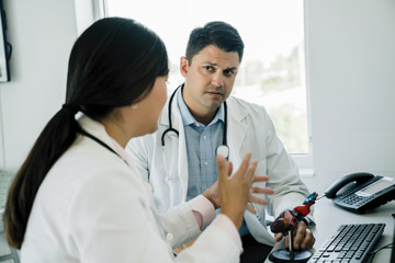 Female doctor discussing over anatomical heart model with colleague