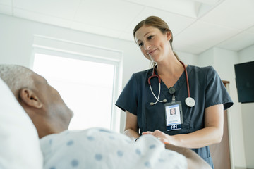 Nurse looking at senior patient in hospital ward