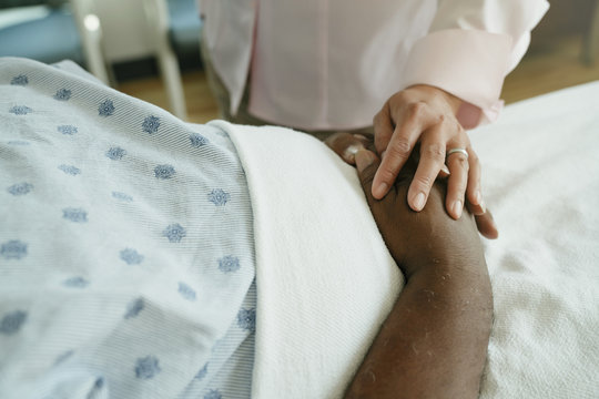 Close-up of doctor comforting senior patient in hospital ward