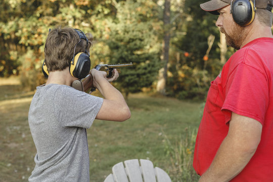 Father looking at son target shooting at backyard