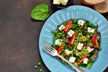 Vegetarian salad with blue cheese, tomatoes, green peas and sesame on a concrete background.